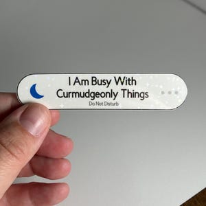 May include: White oval sticker with a crescent moon and the text "I Am Busy With Curmudgeonly Things. Do Not Disturb."