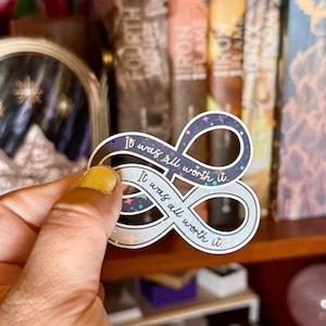 May include: A holographic sticker in the shape of an infinity symbol, with the text "It was all worth it." in a handwritten font. The sticker has a dark blue and silver color scheme with small star accents.