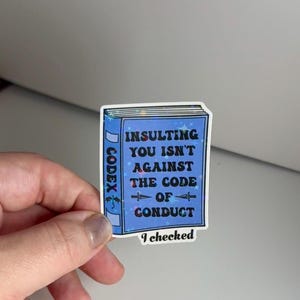 May include: A blue sticker with a book design and the text "INSULTING YOU ISN'T AGAINST THE CODE OF CONDUCT" and "I checked" at the bottom.
