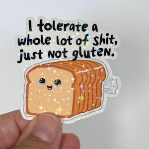 May include: A holographic sticker featuring a cartoon loaf of bread with a smiling face. The sticker has the text "I tolerate a whole lot of shit, just not gluten."