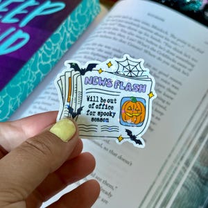May include: A sticker with the text "NEWS FLASH" and "Will be out of office for spooky season." The sticker features a jack-o'-lantern, bats, and a spiderweb design, perfect for Halloween.