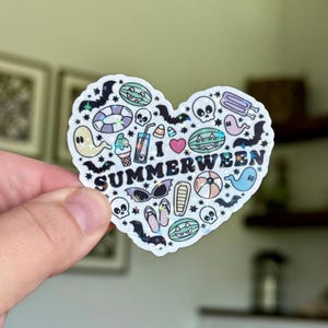 Könnte beinhalten: Ein herzförmiger Aufkleber mit dem Text "I SUMMERWEEN" und Illustrationen zum Thema Sommer und Halloween. Der Aufkleber zeigt Geister, Fledermäuse, Totenköpfe, Eiscreme und Wassermelonenscheiben.