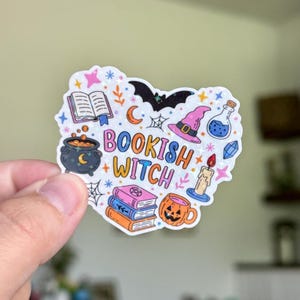 May include: A die-cut sticker featuring the text BOOKISH WITCH in colorful letters surrounded by illustrations of an open book, a black bat, a pink witch hat, a potion bottle, a cauldron, a stack of three books, a candle, and a jack-o'-lantern.