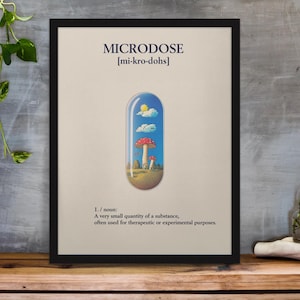 Könnte beinhalten: Ein schwarzer gerahmter Poster mit dem Wort "MICRODOSE" in weißer Schrift und der phonetischen Aussprache in Klammern. Der Poster zeigt eine Cartoon-Illustration einer Pillenkapsel mit Himmel, Wolken und Pilzen darin.