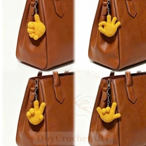 Puede incluir: Cuatro bolsos de cuero marrón, cada uno con un dije de mano de ganchillo amarillo sujeto al lateral. Los dijes muestran diferentes gestos con las manos: un pulgar hacia arriba, un signo de OK, un signo de paz y un signo de te amo, hechos de hilo.
