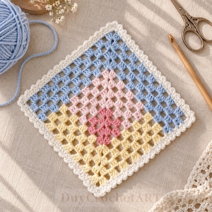 May include: A square crochet granny square featuring a central dark pink diamond, surrounded by layers of light pink, yellow, and light blue yarn, finished with a white scalloped border. A ball of light blue yarn and a wooden crochet hook are nearby.