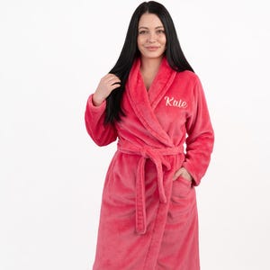 May include: A white ceramic mug with a black handle and the text "But First, Coffee" in a bold, black font. The mug is set against a blurred background, suggesting a cozy setting. The mug appears to be approximately 4 inches tall.