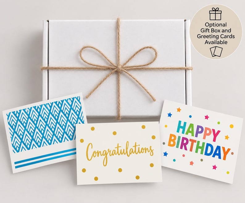 Peut inclure: Une bo&icirc;te cadeau rectangulaire blanche nou&eacute;e avec de la ficelle brune, accompagn&eacute;e de trois cartes de v&oelig;ux. Une carte pr&eacute;sente un motif g&eacute;om&eacute;trique bleu, une autre des pois dor&eacute;s avec le texte Congratulations et la troisi&egrave;me HAPPY BIRTHDAY.