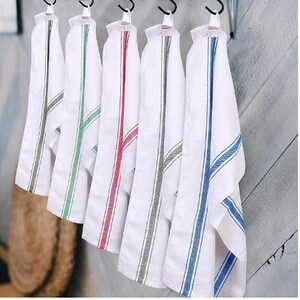 Five white cotton bread tea towels hanging on hooks, each with a different colored stripe: gray, green, red, black and blue.