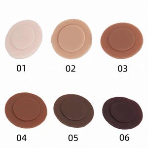 May include: Six circular, flat, disc-shaped objects arranged in two rows of three. Each disc features a smaller, raised circular center. The colors range from a light beige, labeled 01, to progressively darker shades of brown, labeled 02 through 06.