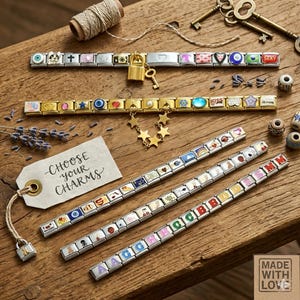 Puede incluir: Una variedad de pulseras de abalorios y abalorios individuales sobre una superficie de madera. Las pulseras presentan diversos diseños, incluyendo letras, símbolos e imágenes coloridas. Una etiqueta dice "CHOOSE YOUR CHARMS". También hay un pequeño candado y llaves.