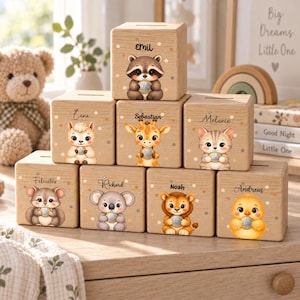 Può includere: Una collezione di otto salvadanai in legno di colore chiaro a forma di cubo, ognuno con un'illustrazione unica di un animale dei cartoni animati e un nome personalizzato stampato sopra. Gli animali includono un procione, lama, giraffa, gatto, topo, koala, leone e pulcino.