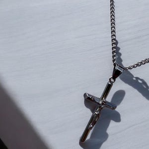 May include: A silver chain necklace with a silver cross pendant featuring a figure of Jesus Christ.