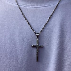 May include: A silver chain necklace with a silver cross pendant featuring a figure of Jesus Christ.