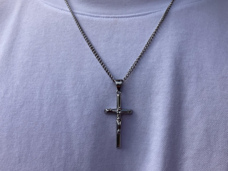 May include: A silver chain necklace with a silver cross pendant featuring a figure of Jesus Christ.