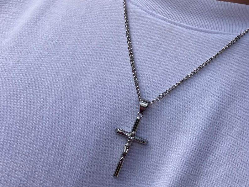 May include: A silver chain necklace with a silver crucifix pendant.