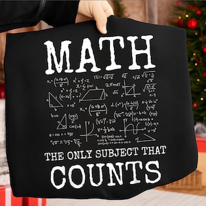 Op de afbeelding: Zwart T-shirt met witte tekst en wiskundige formules. Het woord "MATH" staat bovenaan, gevolgd door vergelijkingen en de zin "THE ONLY SUBJECT THAT COUNTS" onderaan. Een leuk cadeau voor wiskundeliefhebbers.