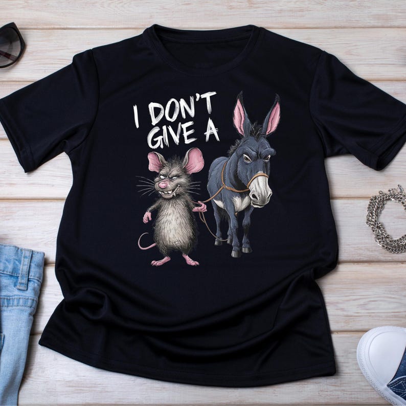 Peut inclure: T-shirt noir avec un dessin d'une souris grise tenant une corde attach&eacute;e &agrave; un &acirc;ne gris. Le texte "I DON'T GIVE A" est imprim&eacute; au-dessus des animaux en blanc.