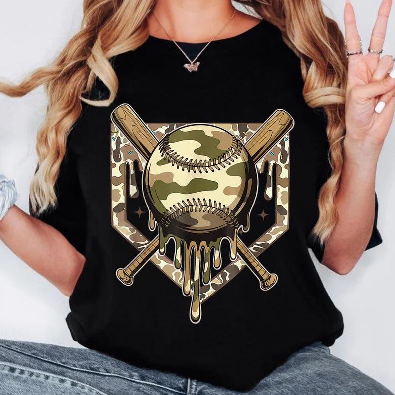 May include: Black t-shirt with a baseball design. The baseball has a camouflage pattern with dripping details. Two crossed baseball bats are behind the baseball. The design is set against a diamond-shaped background.