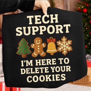 Könnte beinhalten: Schwarzes T-Shirt mit dem Text "TECH SUPPORT" über dem Satz "I'M HERE TO DELETE YOUR COOKIES". Das Shirt zeigt Lebkuchen-Designs eines Weihnachtsbaums, eines Lebkuchenmanns, einer Glocke und einer Schneeflocke.