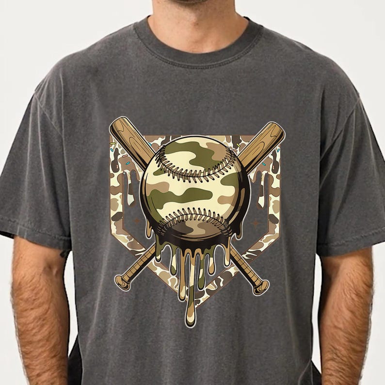 May include: Dark grey t-shirt with a baseball design. The baseball has a camouflage pattern and is dripping. Two crossed baseball bats and a home plate shape complete the design. A casual wear item.