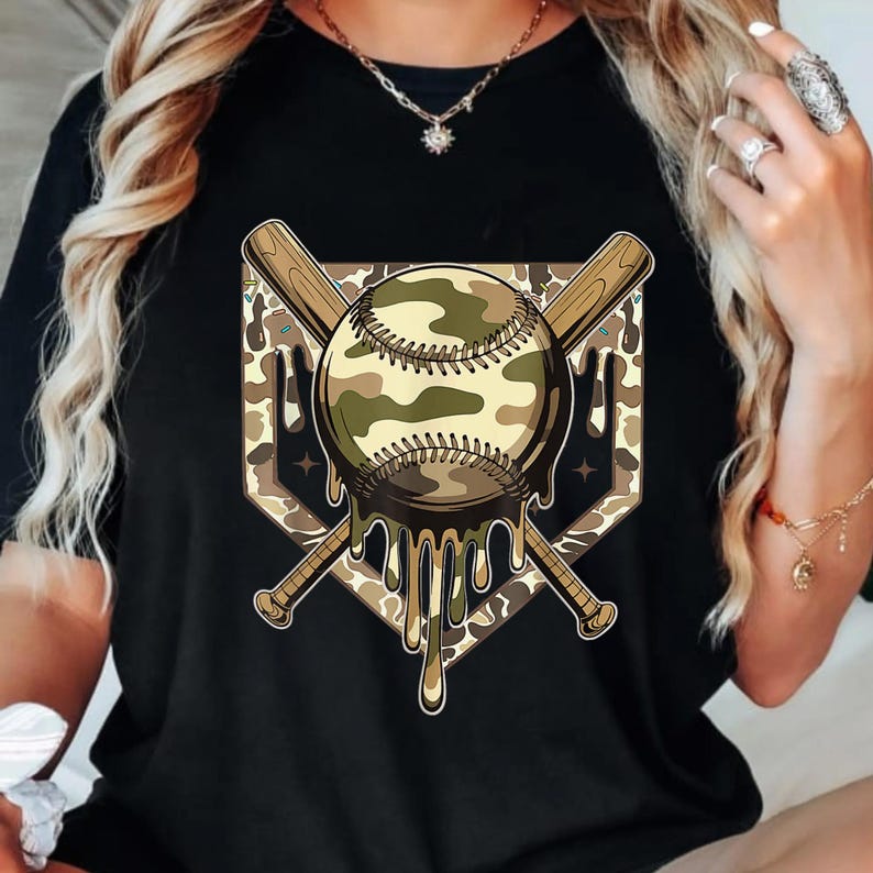 May include: Black t-shirt with a baseball graphic in a camouflage design. The baseball is set over a home plate shape, with two crossed baseball bats behind it. The baseball has a melting effect, with dripping details.