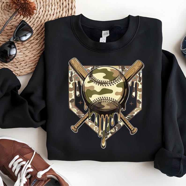 May include: Black sweatshirt with a baseball design. The baseball has a camouflage pattern and is in front of crossed baseball bats. The design includes a dripping effect, and the background is a diamond shape.