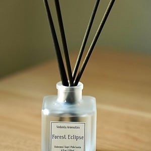 May include: A frosted glass diffuser bottle with black reeds. The label reads "Forest Eclipse" and lists ingredients. The bottle contains 4 fl oz / 120ml of fragrance. The product is designed for home fragrance.