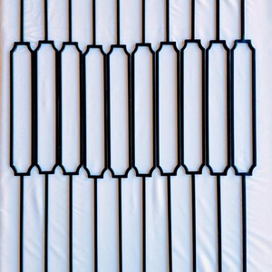 Puede incluir: Un conjunto de estacas decorativas de metal negro para jardín. Cada estaca presenta un marco rectangular con una parte superior decorativa y un tallo largo y delgado. Las estacas están dispuestas en un patrón de cuadrícula sobre un fondo blanco.