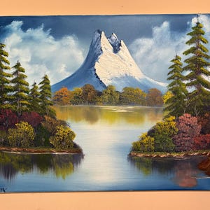 Bob Ross inspired landscape oil painting with mountain and river scene using bright colors on a 16 x 20 stretched canvas.