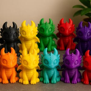 Könnte beinhalten: Eine Sammlung farbenfroher Drachenfiguren in verschiedenen Farbtönen, darunter Schwarz, Gelb, Grün, Rot, Lila, Orange, Rosa und Blau. Jeder Drache hat Hörner, Flügel und einen freundlichen Gesichtsausdruck. Die Figuren sind auf einer grauen Oberfläche angeordnet.