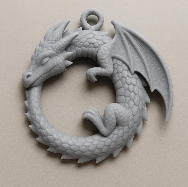 May include: A gray dragon pendant in a circular design, with the dragon biting its own tail. The pendant features detailed scales, wings, and a loop for hanging. The dragon is a mythical creature, often associated with fantasy and medieval themes.