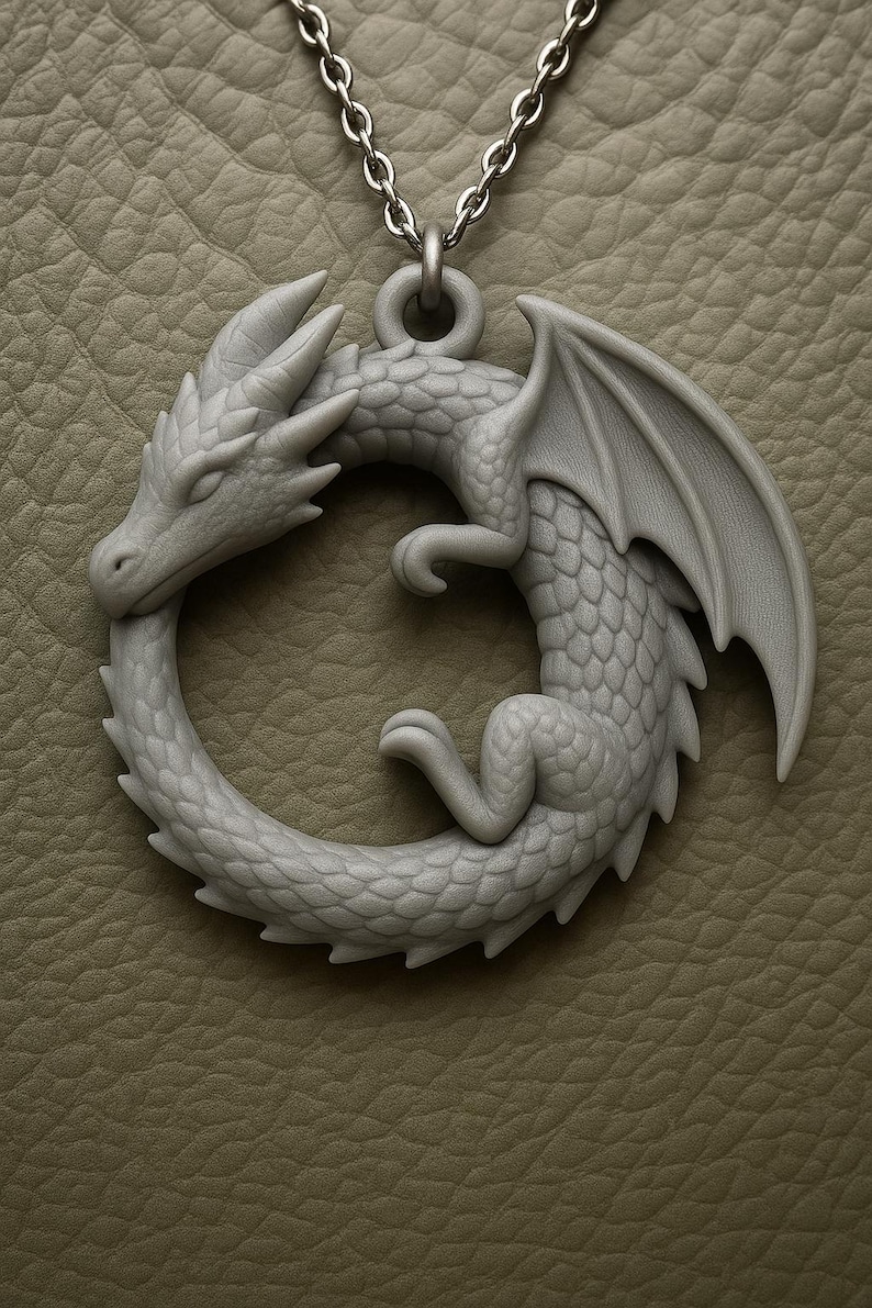 May include: A gray dragon pendant with a detailed, scaled body and outstretched wings. The dragon is in a circular pose, biting its tail, and is suspended from a silver chain. The pendant is approximately 2 inches in diameter.