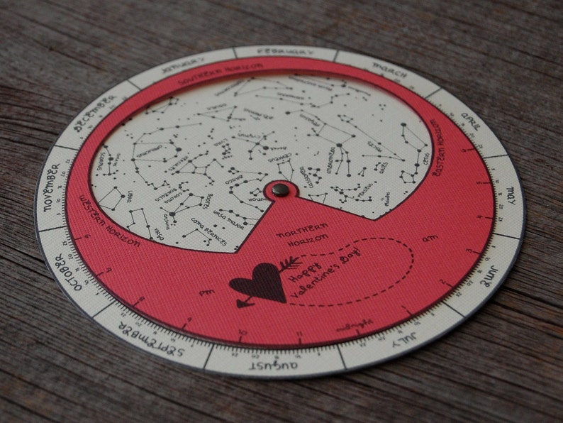 K&ouml;nnte beinhalten: Eine rote und wei&szlig;e Sternenkarte aus Papier mit einem schwarzen Herzen und dem Text "Happy Valentine's Day!" Die Karte zeigt die Sternbilder, die im Laufe des Jahres am Nachthimmel sichtbar sind.