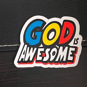 May include: A white sticker with the words "GOD IS AWESOME" in bold, black letters. The word "GOD" is in a bubble-like shape with the letters coloured blue, yellow, and red.