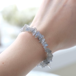 Peut inclure: Un bracelet en éclats de labradorite bleu clair. Le bracelet est porté au poignet.