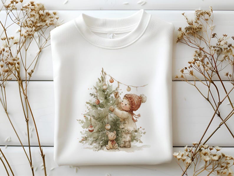 Pode incluir: Camisola branca com uma ilustra&ccedil;&atilde;o em aquarela de uma crian&ccedil;a decorando uma &aacute;rvore de Natal com enfeites. A crian&ccedil;a usa um chap&eacute;u e casaco vermelhos, com um ursinho de pel&uacute;cia por perto. Tema de f&eacute;rias aconchegante e festivo.
