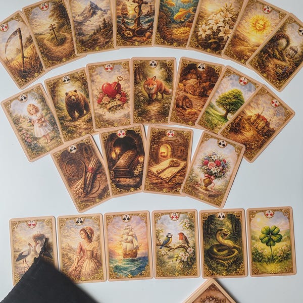Könnte beinhalten: Ein Satz Tarotkarten mit verschiedenen Illustrationen, darunter ein Kreuz, ein Anker, ein Fuchs und ein Bär. Die Karten sind fächerförmig angeordnet, mit einem schwarzen Samtbeutel und einem Kartenspiel in der unteren rechten Ecke.