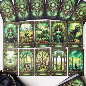 K&ouml;nnte beinhalten: Ein Tarotkartenspiel mit einem schwarzen Samtbeutel. Die Karten zeigen detaillierte Illustrationen in Gr&uuml;n-, Gold- und Schwarzt&ouml;nen. Die Kartenr&uuml;ckseiten haben ein florales Design. Das Deck enth&auml;lt Karten mit Figuren und Szenen.