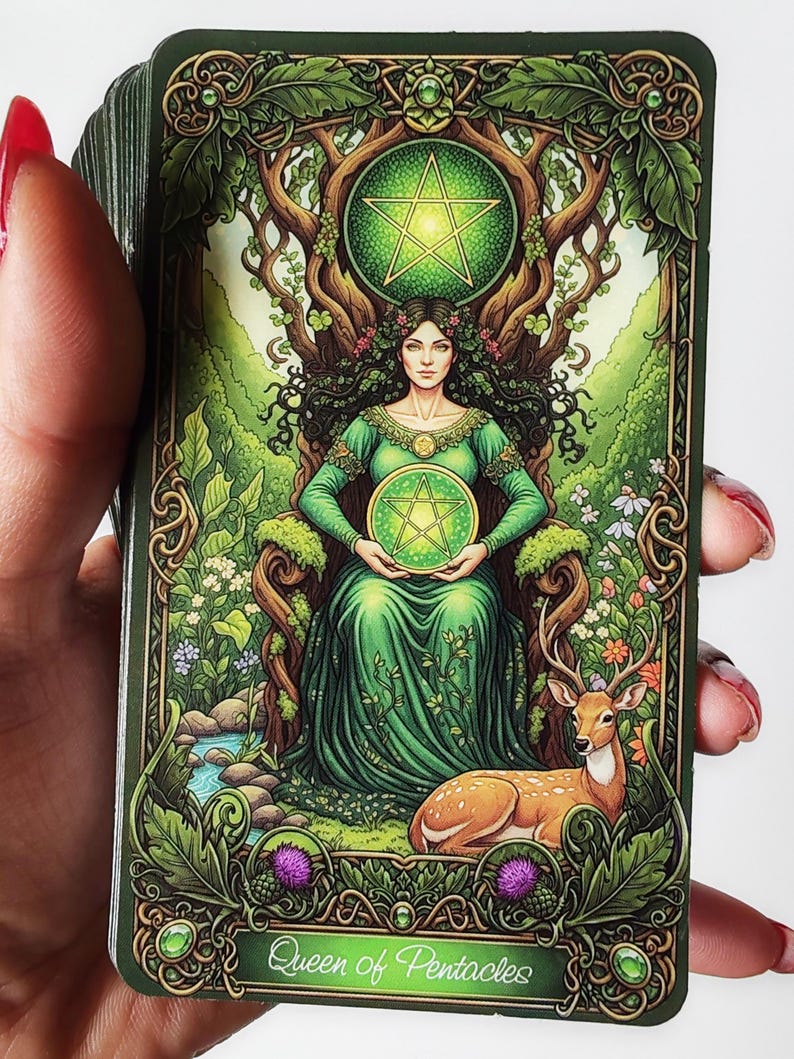 K&ouml;nnte beinhalten: Tarotkarte mit einer Frau in einem gr&uuml;nen Kleid auf einem Thron aus &Auml;sten, die ein gr&uuml;nes Pentakel h&auml;lt. Ein Hirsch liegt in der N&auml;he. Die Karte tr&auml;gt die Aufschrift "Queen of Pentacles".