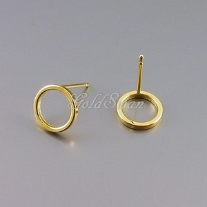 May include: A pair of gold-toned circle stud earrings. The earrings are simple and minimalist, with a smooth, polished finish.