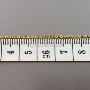 May include: A gold chain measuring 6 cm in length, as shown on a ruler.