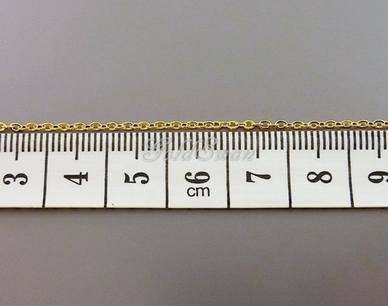 May include: A gold chain measuring 6 cm in length, as shown on a ruler.