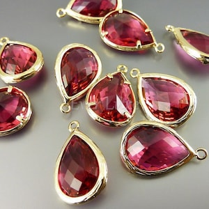 May include: A group of ten teardrop-shaped crystal charms with gold-tone settings. The charms are a deep pink colour and have a faceted design. They are perfect for adding a touch of sparkle to jewellery projects.