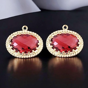 May include: A pair of gold-tone earrings with red oval-shaped gemstones set in a decorative frame.