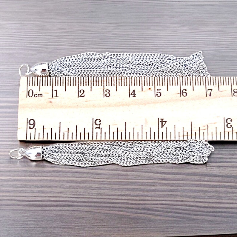 Peut inclure: Deux glands en cha&icirc;ne argent&eacute;e, mesurant chacun environ 18 cm de long, sont pr&eacute;sent&eacute;s sur un fond en bois. Une r&egrave;gle est utilis&eacute;e pour montrer la longueur des glands.