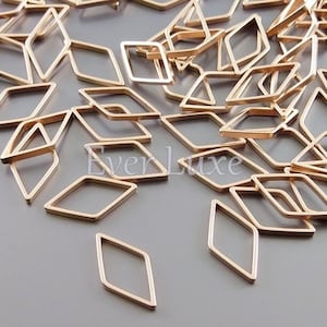 May include: A collection of small, open-frame diamond shapes in a warm gold color. The geometric components are scattered across a neutral surface, creating a delicate and artistic display. These components are ideal for jewelry making and crafting.