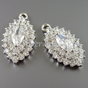 Puede incluir: Dos colgantes de plata con un gran cristal de imitaci&oacute;n transparente en forma de marquesa rodeado de cristales de imitaci&oacute;n transparentes m&aacute;s peque&ntilde;os.