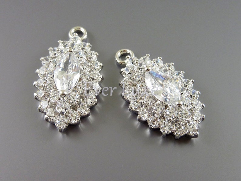 Puede incluir: Dos colgantes de plata con un gran cristal de imitaci&oacute;n transparente en forma de marquesa rodeado de cristales de imitaci&oacute;n transparentes m&aacute;s peque&ntilde;os.