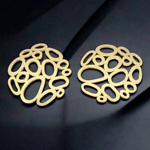 May include: A pair of gold-toned earrings with a geometric design featuring a cluster of interconnected circles and ovals.
